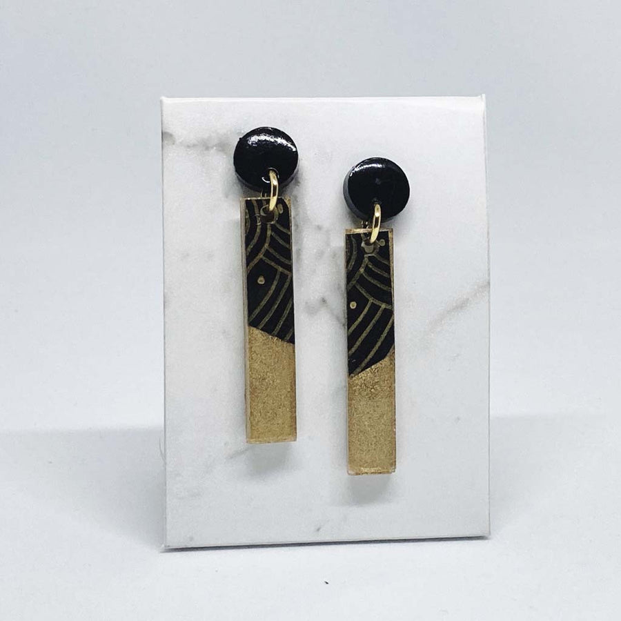 Two long rectangular shaped earrings made from black and gold resin